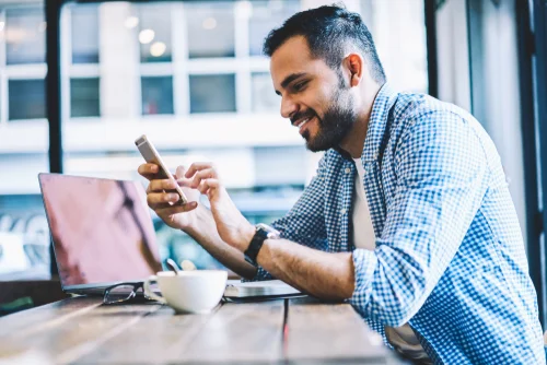 man sitting at desk looking at phone