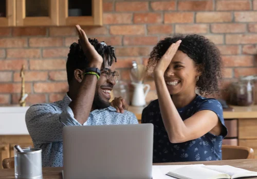 A couple happy to see they can skip a payment on their loan on their laptop