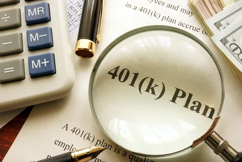 magnifying glass on top of a 401(k) plan paperwork with calculator