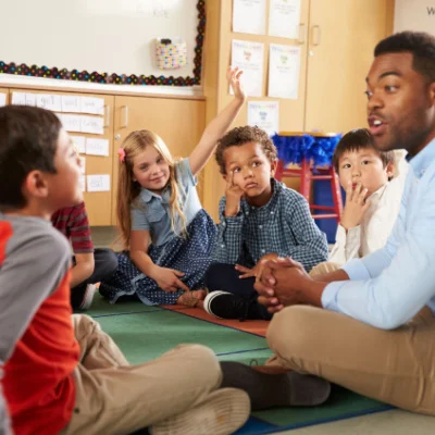 A teacher sitting with his students talking to them