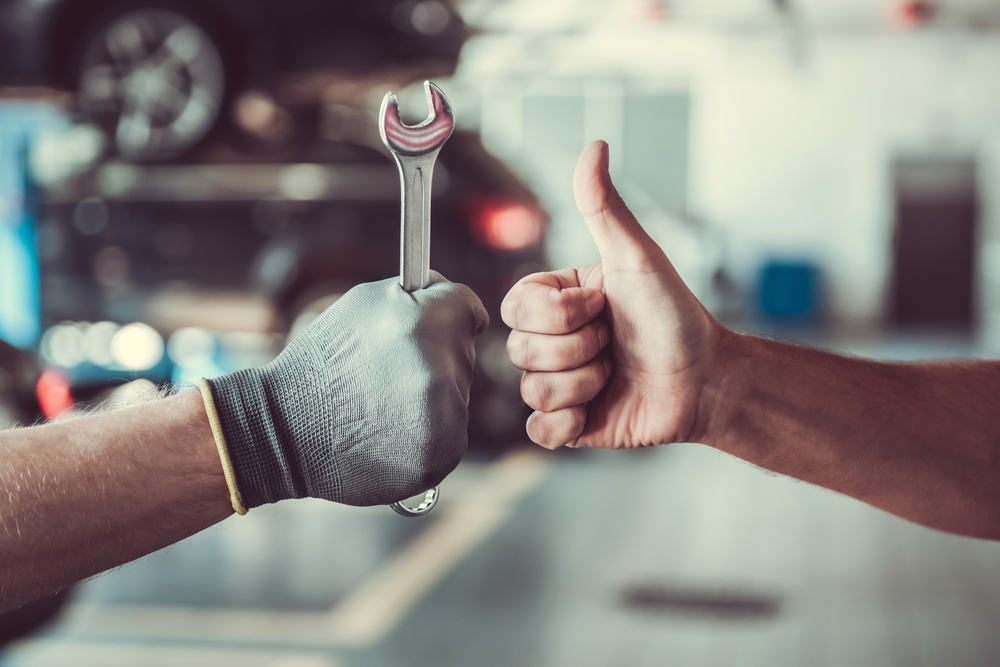 Mechanic with tool and member with thumbs up