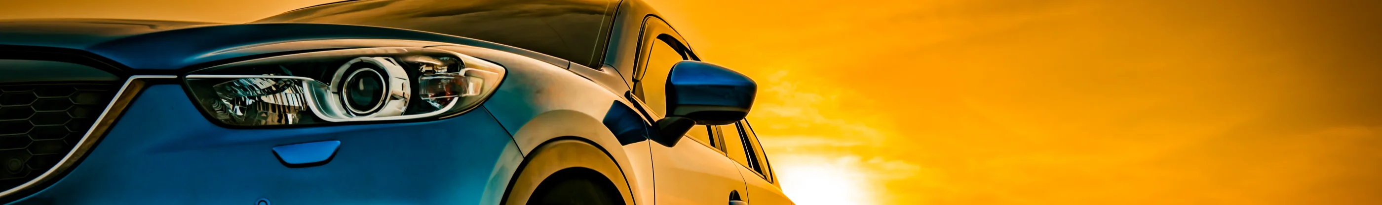 Picture of a blue car with a sunset in the back