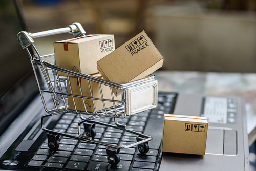 miniature shopping cart filled with boxes and sitting on top of a keyboard