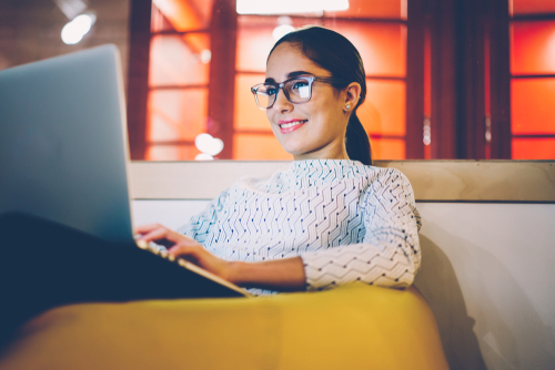 woman on couch smiling looking at computer screen