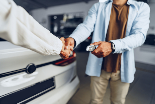 two people handshake inside new car dealership