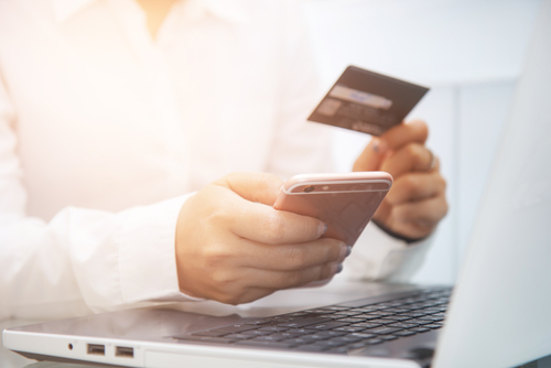 person holding phone and credit card to make payment