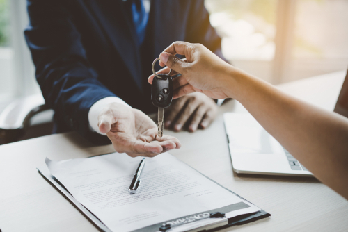 paperwork on desk and person being given set of car keys