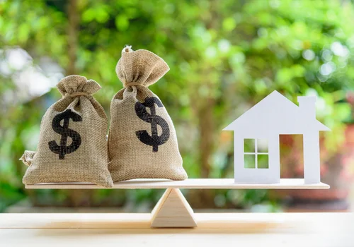 a balance which has two money bags on the left and a cut out of a house on the right
