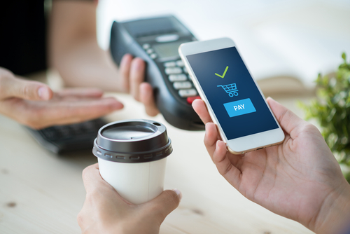 person holding coffee and using phone and mobile pay