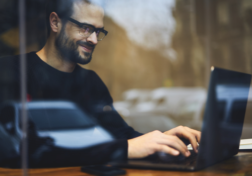 person typing on keyboard next to window