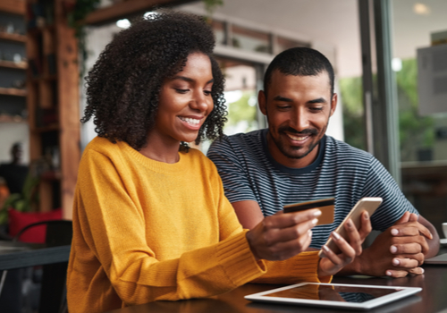 Couple looking at a credit card and paying for something on their phone.