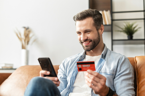 man holding credit card and phone smiling