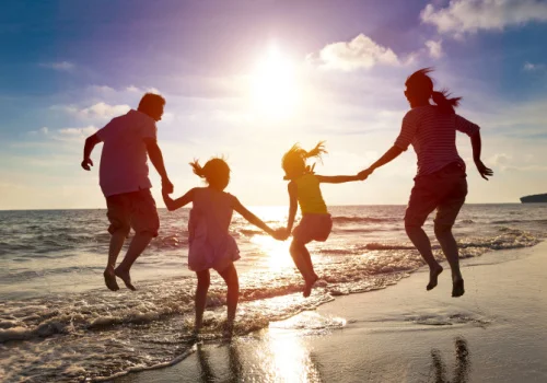 A family running into the sun set into the beach