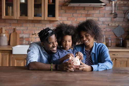 A family teaching their child to save in a piggy bank 