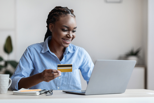 person holding a credit or debit card while making a purchase online