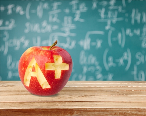 apple on desk in front of chalk board