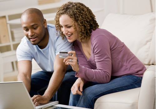 A couple on the sofa looking the their credit card benefits on their laptop