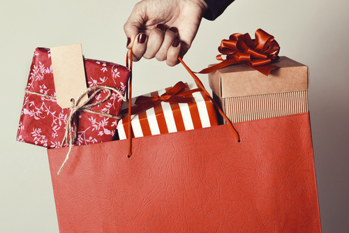 red bag filled with wrapped gifts held by a hand