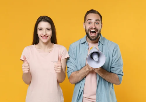 a woman is giving a double thumbs up and a exited man is next to her with a bullhorn 