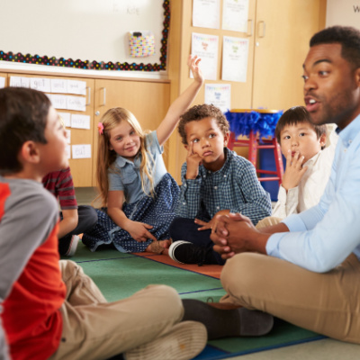 A teacher sitting with his students talking to them