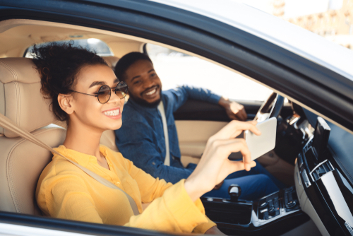 man and woman inside car taking picture with phone
