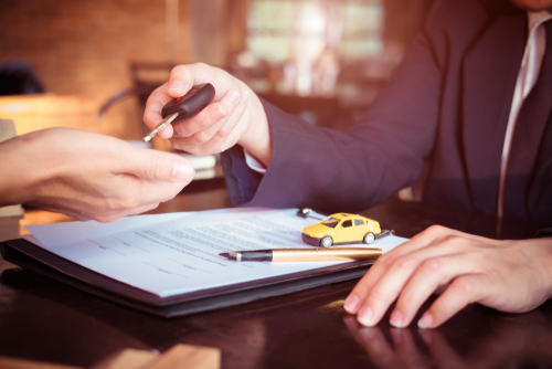 car loan paperwork being signed and person being handed car keys