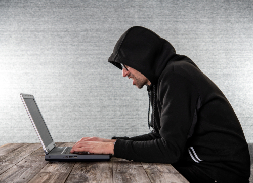 A man in a black hoodie on a computer