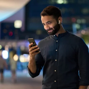 A guy using his phone at night and smiling
