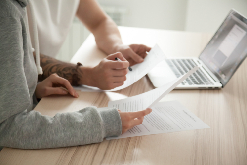 people discussing paperwork in front of computer