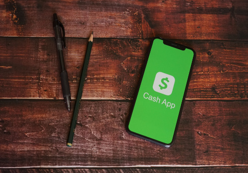 A1 iPhone 11 with the "cash App" open on a wood table next to two pencils. 