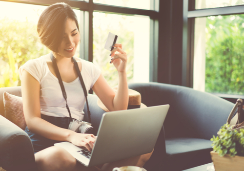 A woman is looking the benefits of her credit card on a laptop in get Livingroom during a sunset. 