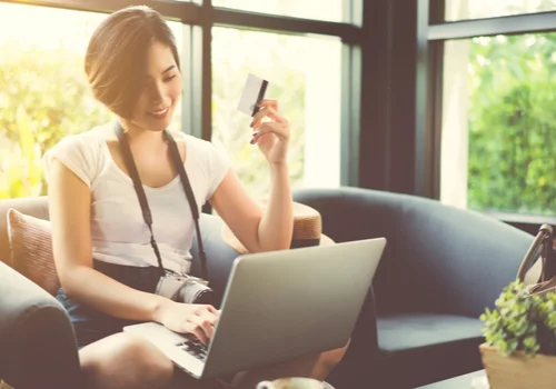 A woman is looking the benefits of her credit card on a laptop in get Livingroom during a sunset.