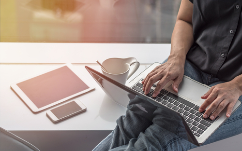 person sitting by window with tablet and computer