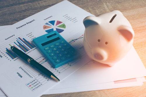 savings paperwork with calculator and piggy bank sitting on top of it