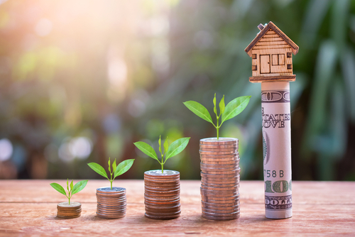 stacks of coins lined up with a small toy house on the highest stack to symbolize increasing your home value