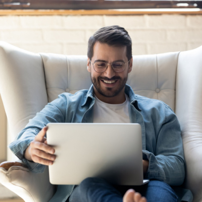 a happy guy on this laptop on a sofa